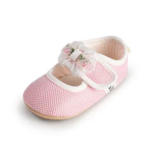 Detail view of a pink mesh baby girl princess shoe with floral lace bow.