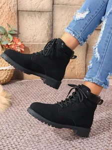 Close-up of stylish black suede lace-up Martin boots for women featuring a thick lug sole