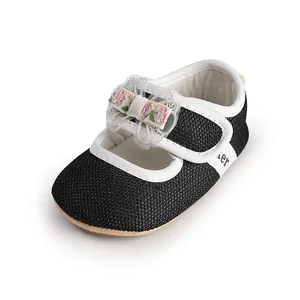 Close-up of a black baby princess shoe featuring a floral embroidered bow detail