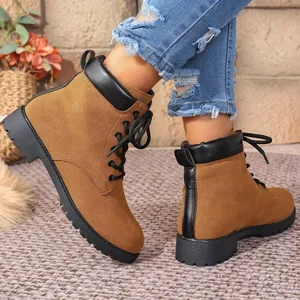 Close-up detail of tan suede lace-up Martin boots featuring a black leather collar trim