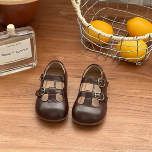 Retro brown girl's Mary Jane princess shoes with double buckle straps on wooden table.