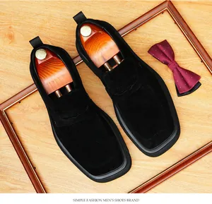 Primer plano de mocasines de ante negro para hombre con punta cuadrada sobre madera