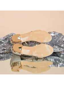 Vue de dessous de sandales dorées à petit talon avec décoration de strass brillants