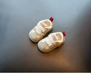 Détail de chaussures de marche pour bébé beiges avec velcro et languettes rouges