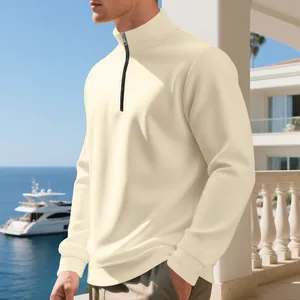 Close-up of a men's cream quarter-zip fleece sweatshirt in a luxury resort background