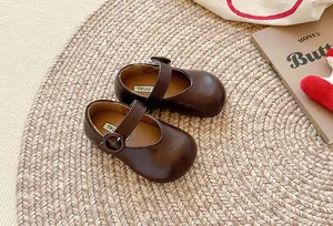 Detailansicht brauner Mary Jane-Kinderschuhe aus Leder auf einer stilvollen Strohmatte