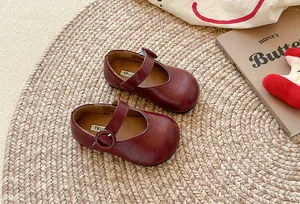 Detail von burgunderroten französischen Kinder-Leder-Mary-Janes auf einer Matte