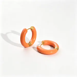 Detailed view of vibrant orange enamel C-shape hoop earrings with golden stainless steel