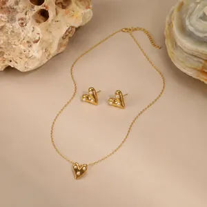 Vintage gouden hartvormige ketting en oorbellen set met witte parels op stenen decor