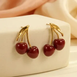 Macro view of vintage enamel cherry earrings with glossy red finish and golden stems