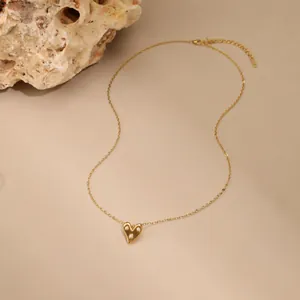 Detailopname van een vintage gouden harthanger ingelegd met drie kleine pareltjes.