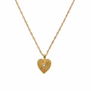 Close-up of a gold-plated textured heart pendant necklace with a central sparkling stone.