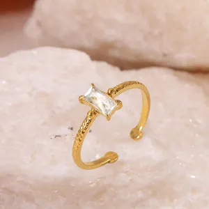 Gros plan d'une bague dorée torsadée avec un zircon rectangulaire étincelant.