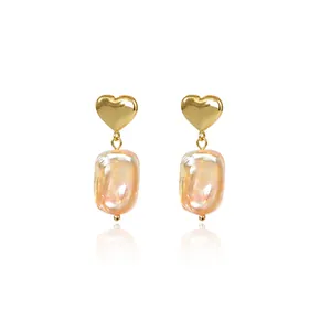 Vue détaillée macro de clous d'oreilles cœur doré avec perles baroques roses pendantes