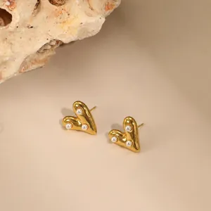 Gedetailleerd overzicht van vintage gouden hartjes oorknopjes met drie parels.