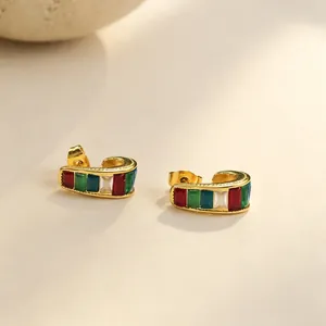 Primer plano de pendientes de acero inoxidable dorado con circonitas rectangulares.