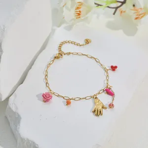 Detailansicht eines vergoldeten Armbands mit bunten Harzrosen und Anhängern.