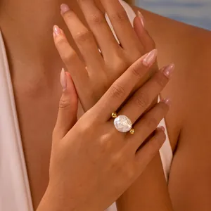 Détail d'une bague élégante en perle baroque avec des accents dorés sur la main du mannequin