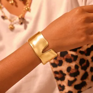 Gros plan d'un large bracelet manchette en acier inoxydable doré en forme de vague