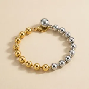 Detailed view of a two-tone gold and silver beaded bracelet with lobster clasp.