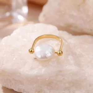 Gros plan sur une bague élégante en perle baroque et anneau doré sur pierre blanche
