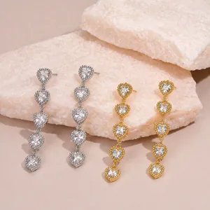 Gros plan de boucles d'oreilles pendantes avec cinq cœurs sertis de strass.