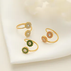 Nahaufnahme von drei vergoldeten Emaille-Gänseblümchen-Ringen auf weißem Seidenhintergrund.