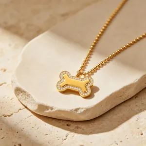 Détail d'un collier avec pendentif en forme d'os en acier doré orné de zircons brillants.