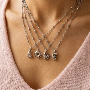 Detailed shot of silver bubble letter LOVE pendants on a stainless steel bead chain necklace
