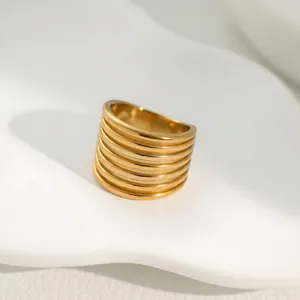 Close-up detail of a minimalist gold-finished wide band ring with layered texture