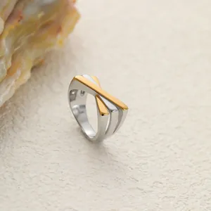 Détail d'une bague croisée bicolore en acier inoxydable au design de feuille dorée et argentée