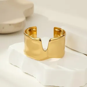 Gros plan d'un bracelet manchette irrégulier en acier inoxydable doré avec bords ondulés.