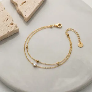 Close-up of elegant double-layer gold bead bracelet with a single sparkling zircon