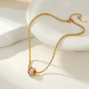Detalle de collar de cuentas doradas con colgante de piedra rosa para un estilo elegante y diario.