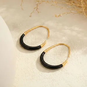Detailed macro view of vintage gold-plated C-shaped earrings with black enamel inlay