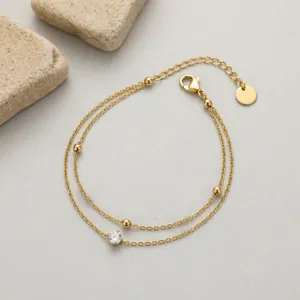 Detail view of a double-layer minimalist gold bracelet with bead and stone accents.