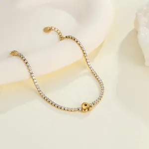 Nahaufnahme eines goldenen Tennisarmbands aus Edelstahl mit einem Anfangsanhänger