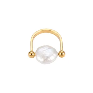 Détail d'une bague élégante avec perle baroque blanche et monture dorée raffinée en forme de U
