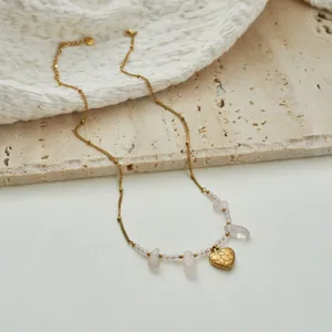Detailed view of stainless steel necklace with rose quartz and gold heart pendant
