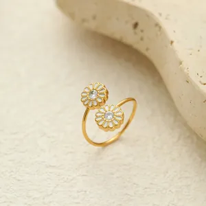 Detail eines vergoldeten Edelstahlrings mit zwei weißen Gänseblümchen aus Emaille.