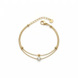 Detailed view of a minimalist double-layered gold bracelet with beads and single crystal.