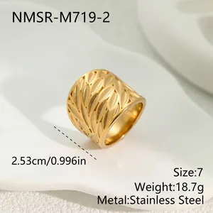 Close-up detail of a wide gold stainless steel ring with hollow leaf pattern texture