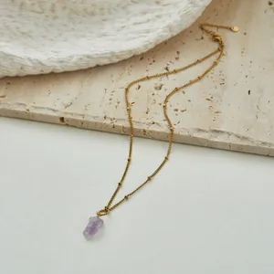 Detailed view of a gold satellite chain necklace with raw purple amethyst pendant