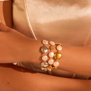 Close-up detail showing elegant gold and silver baroque pearl bracelets on a model's wrist