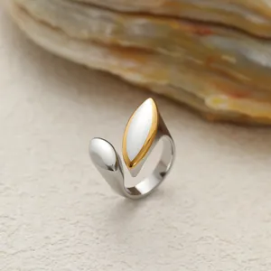 Gros plan d'une bague ouverte en acier bicolore avec des détails fluides en forme de feuille.