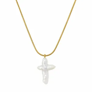 Détail macro d'un collier en acier inoxydable doré avec pendentif croix en perle baroque
