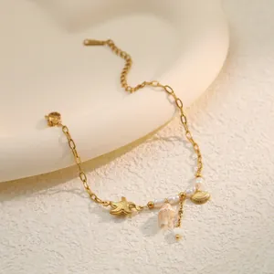 Detail macro view of golden stainless steel bracelet with starfish pearl and sea shell charms