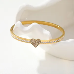 Detail view of a gold-plated stainless steel bangle with a pavé heart and crystals.