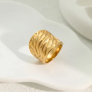 Macro view of golden hollowed leaf pattern on a wide stainless steel band ring
