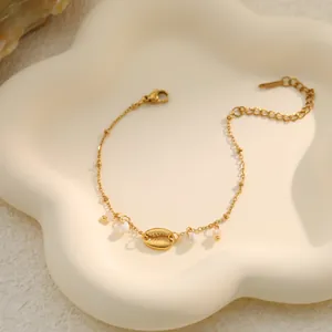 Close-up of gold stainless steel bracelet with shell and pearl details